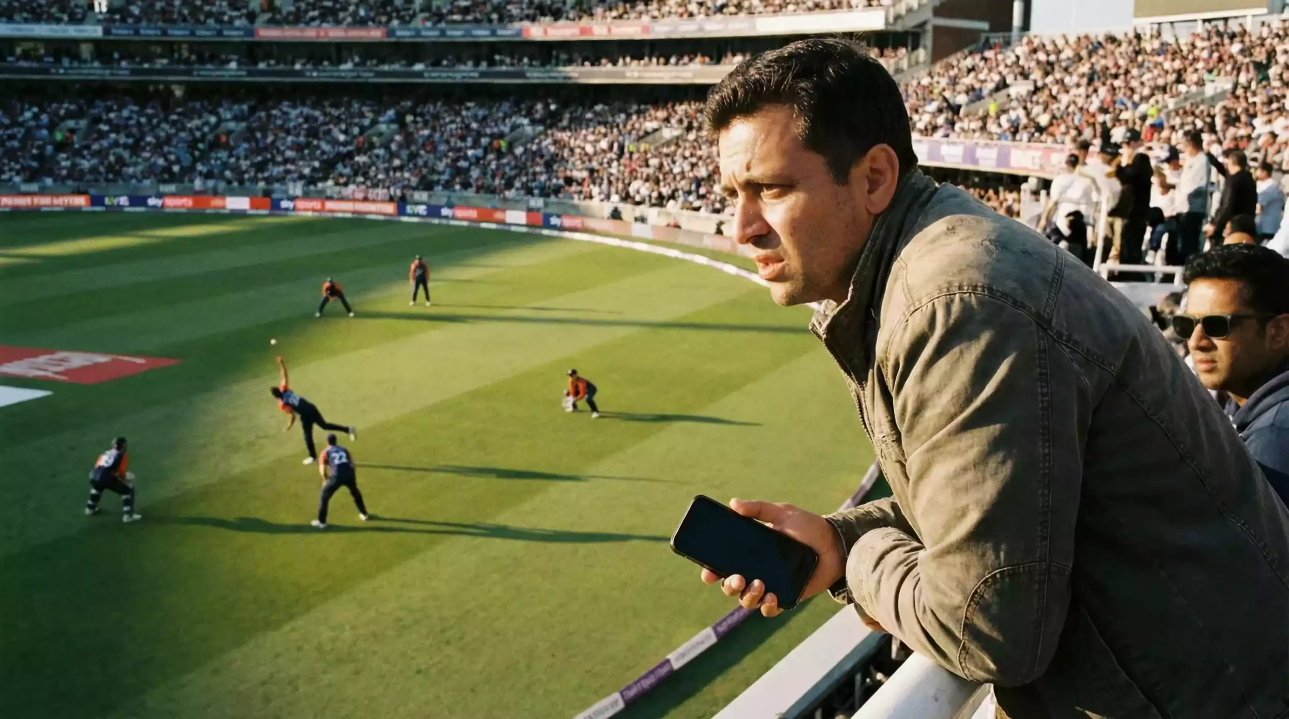 Cricket fan watching a tense match moment with a phone in hand at a stadium