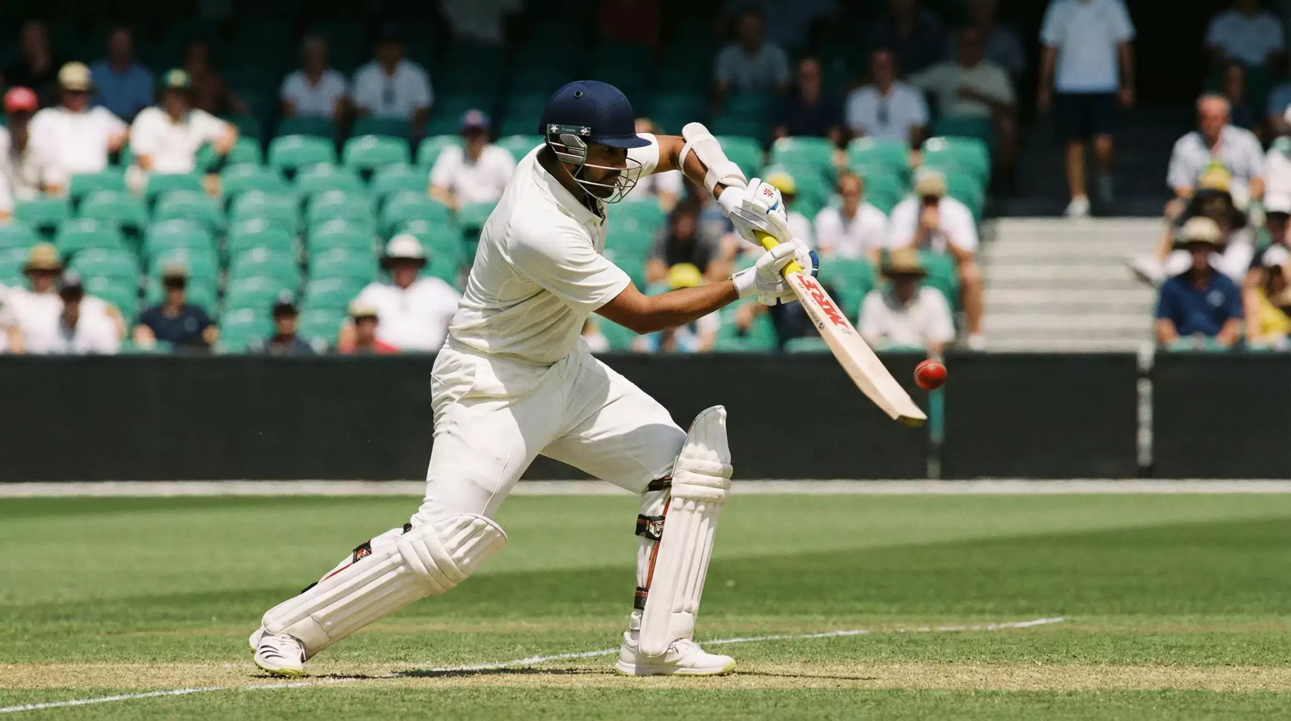 Cricket batter playing a shot in a packed stadium during a day match